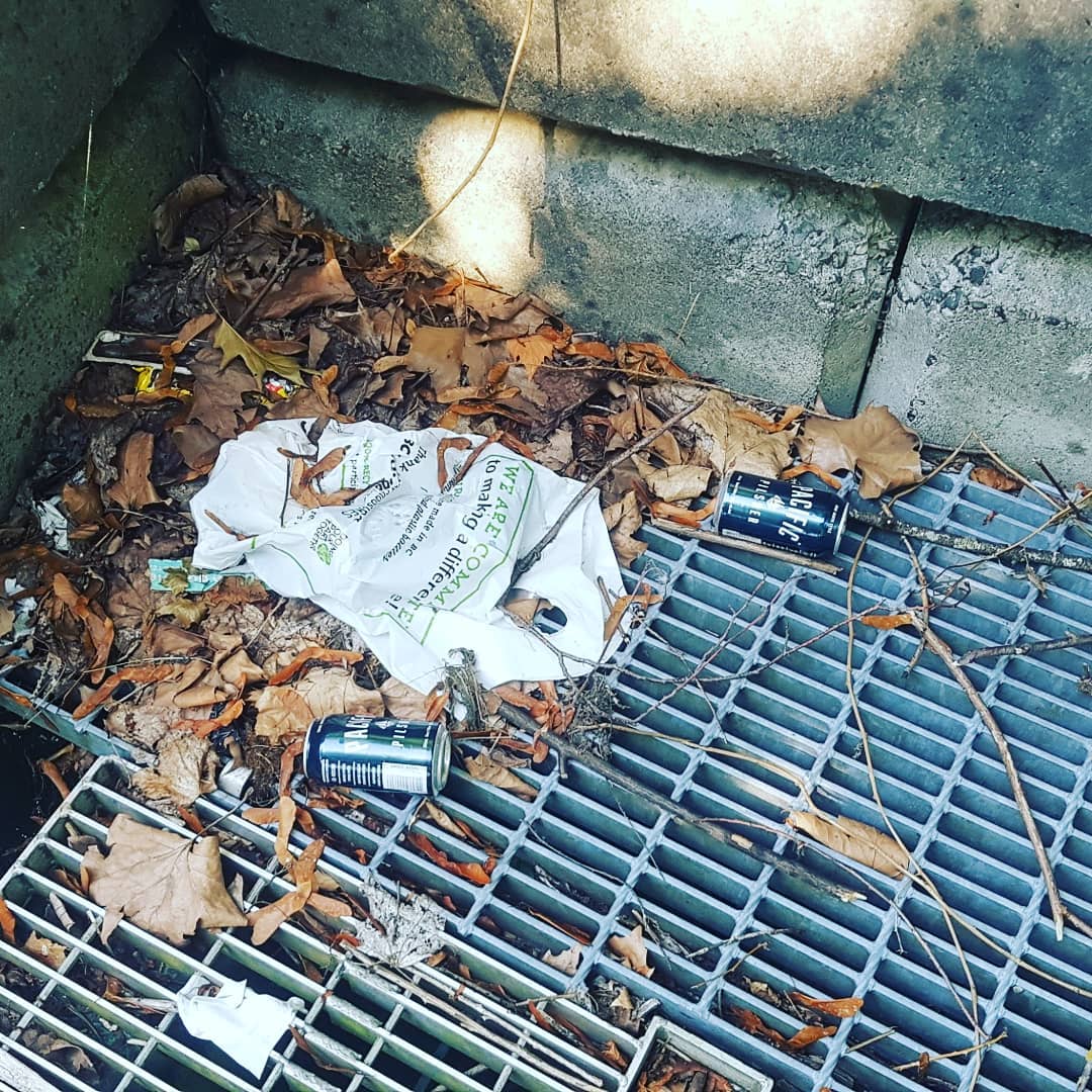 Some trash rests on the grates of a waterway near Still Creek.
