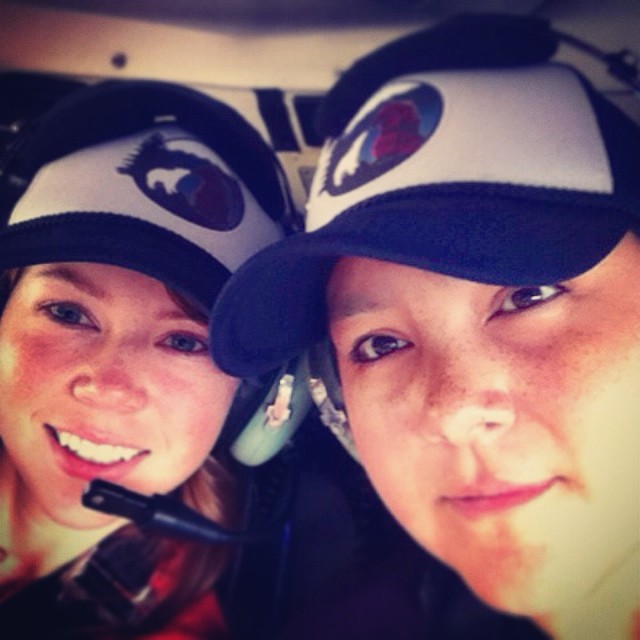 Two women wearing raincoast staff caps inside a helicopter