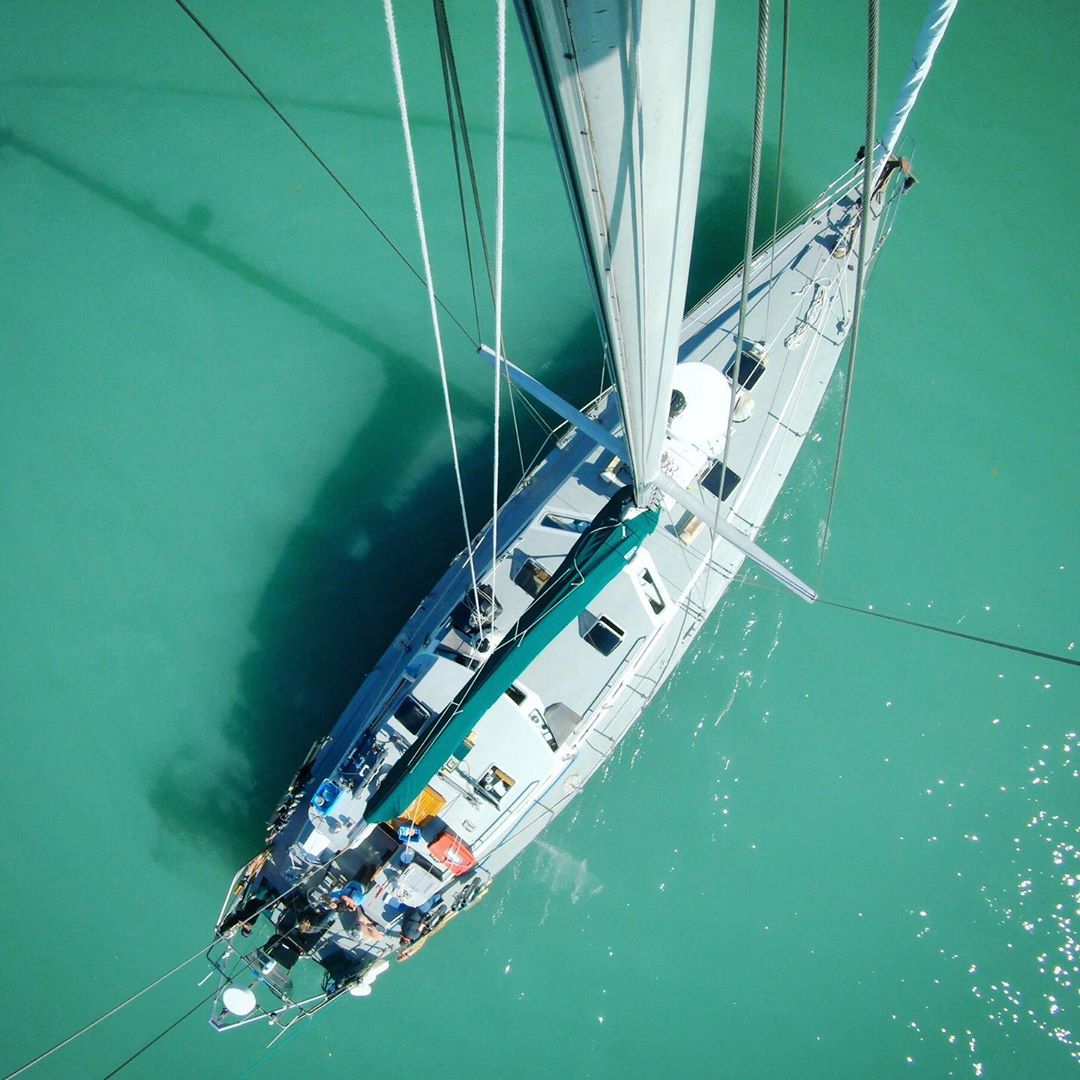 Aerial shot of the Achiever, Raincoast's research vessel, a white boat with white sails