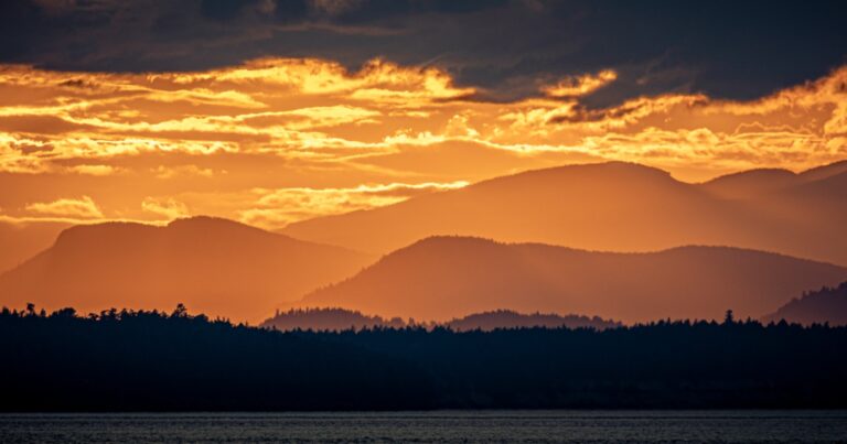 A golden sunset reveals layers of mountains.