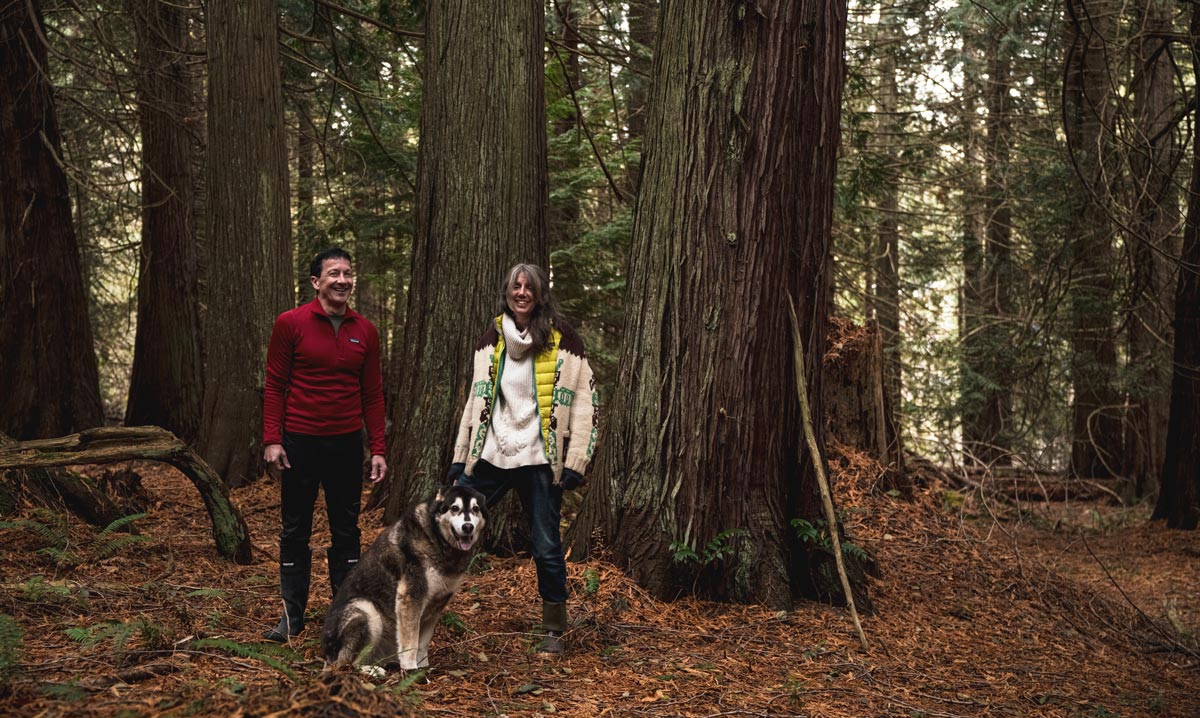 Chris Genovali and Misty MacDuffee and Atticus stand in the forest on Pender Island.
