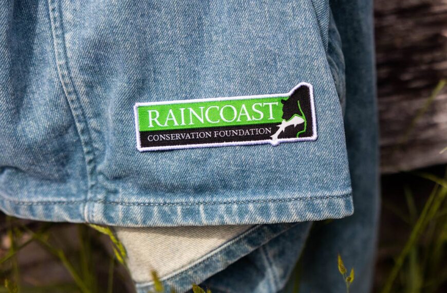 A Raincoast Conservation Foundation patch of the Raincoast logo rests on the bottom of a denim pant leg or maybe a skirt.
